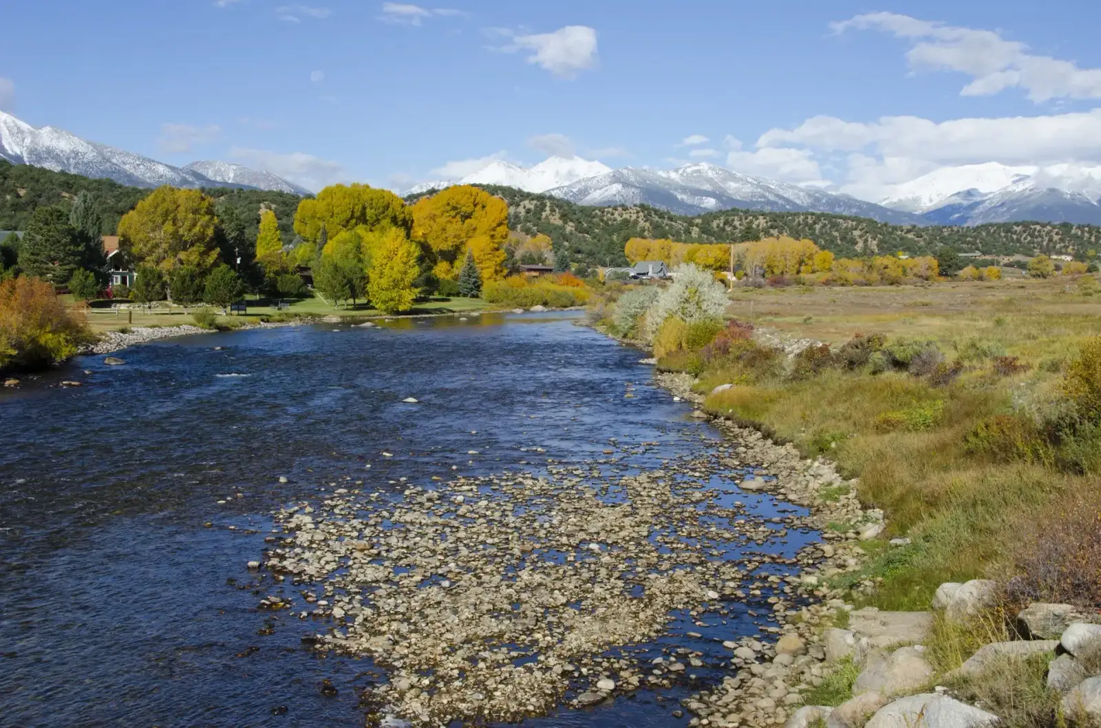 The Arkansas River winding through golden cottonwoods beneath snow-capped Colorado mountains